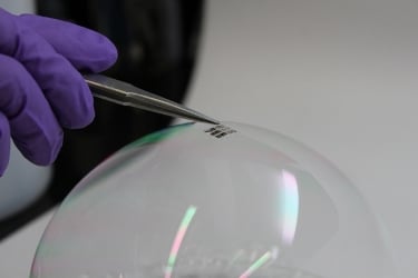 MIT researchers place a lightweight solar cell on top of a soap bubble. Image source: Joel Jean and Anna Osherov.