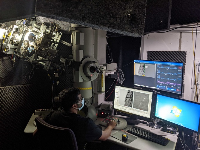 The real-time quantification and visual overlay can be seen in the top monitor where the researcher tries to quantify the number of large black dot defects as an evolution of radiation damage. Source: Kevin Field, University of Michigan Nuclear Oriented Materials and Examination Group
