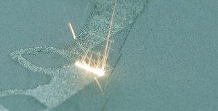 A laser beam heats a metal powder to additively build a product layer by layer.Image source: Darpa.mil