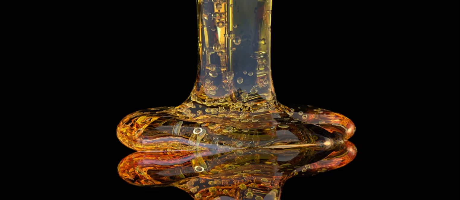 Viscous amber fluid pours and pools against a black background. Source: Buddha Elemental 3D/Unsplash