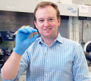 Dwight Seferos, associate professor in the University of Toronto's Department of Chemistry, holds the nickel-sized prototype. Image credit: Diana Tyszko.