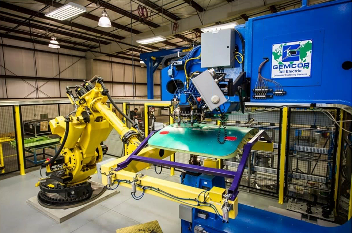 Secondary encoder control enables a robot to position a panel with very high precision for another robot that will perform drilling and riveting operations on the panel. Source: FANUC America