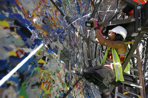 Jared Chen works at reinforcing panels inside a blue whale art piece made from discarded single-use plastic at Crissy Field. Source: AP Photo/Eric Risberg