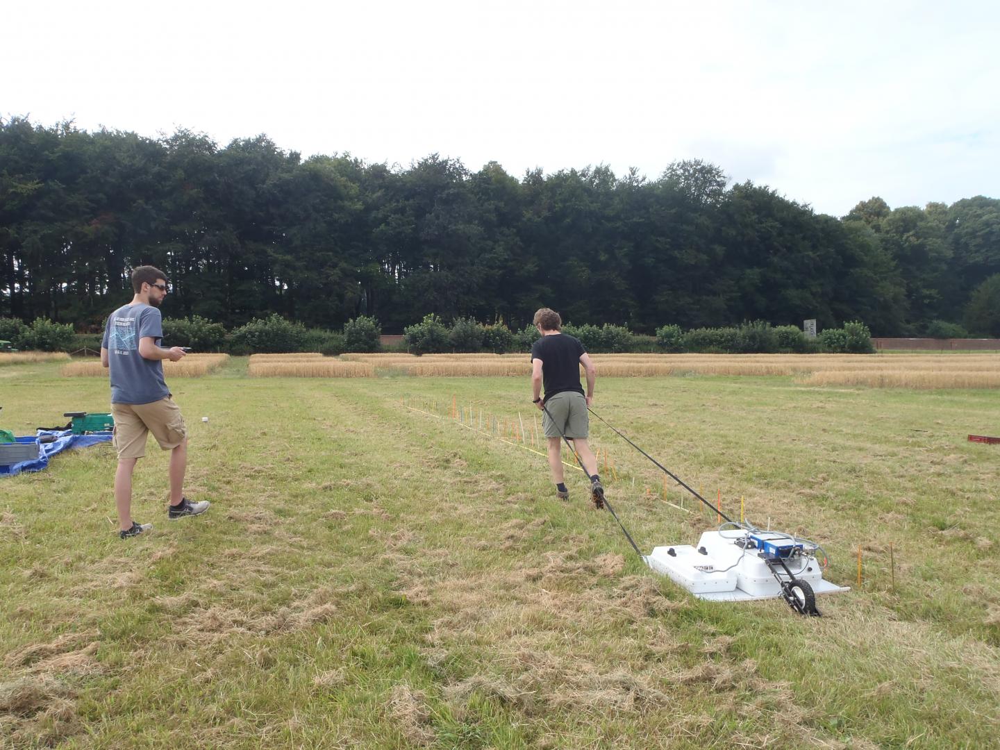 Algeo stands on the left with a tablet while his advisor, Lee Slater, drags ground penetrating radar equipment over the soil's surface. Source: Chris Watts, Rothamsted Research