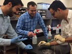Navid Kazem (left), Jonathan Malen (center), and Carmel Majidi (right) demonstrate the elasticity of a strip of &ldquo;thubber."