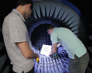 Amin Momeni (l) illuminates the antenna-testing chamber while Nader Behdad installs a phased-array antenna. Image credit: Stephanie Precourt.