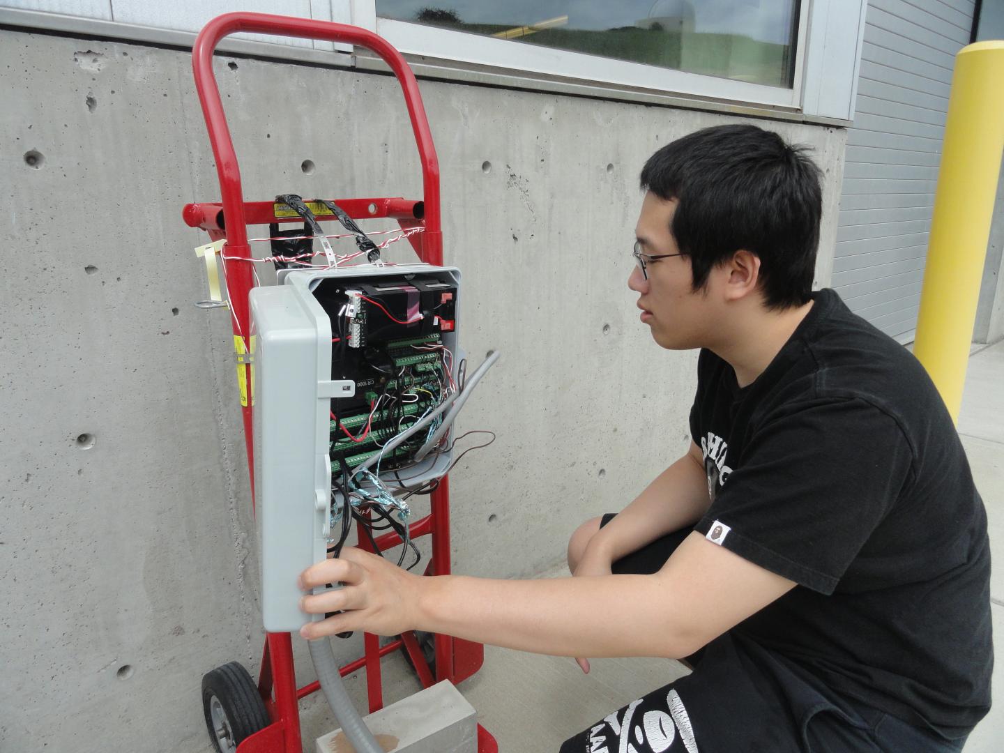 Chemical engineering student Ka Fung Wong looks at the data log, which is used to gather data from sensors buried under the concrete test plot. (Source: WSU)