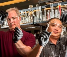 Sandia researchers Michael Hibbs (l) and Cy Fujimoto demonstrate the clarity of the new membrane. Image credit: Randy Montoya.
