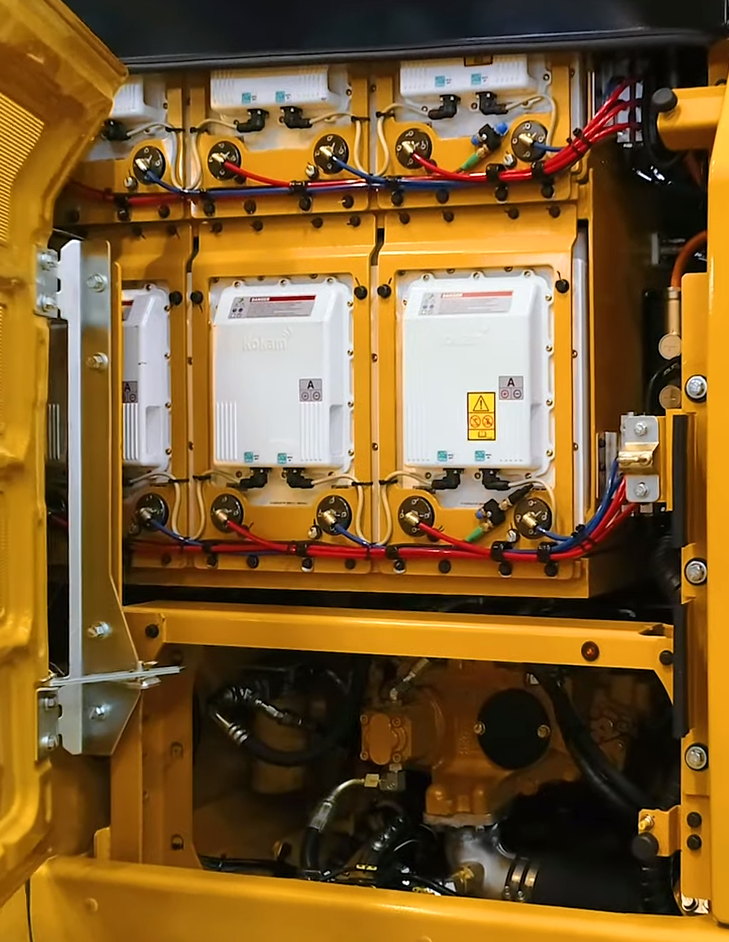 Behind the hatch of the Cat 323F Z-line. The hydraulic pump is seen below a large stack of batteries. Source: Pon Cat