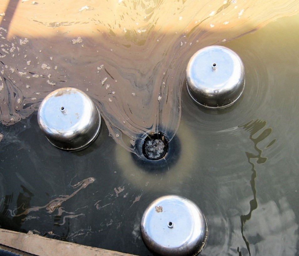 Figure 1: A weir-type oil skimmer, showing three stainless-steel body floats and black floating weir at center. Source: Gprender/CC BY-SA 4.0