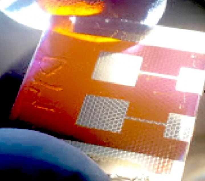 A compound solar cell illuminated from a light source below. Hexagonal scaffolds are visible in the regions coated by a silver electrode. The new solar cell design could help scientists overcome a major roadblock to the development of perovskite photovoltaics. Source: Stanford University