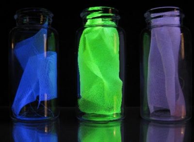 Examples of the silk used in experiments to detect damage in composites, shown under black light. (Left) Ordinary fibroin of the Bombyx mori silk worm. The observed fluorescence is the result of molecules already present in the protein structure of the fiber. (Middle) Mechanophore-labeled silk fiber fluoresces in response to damage or stress. (Right) Control sample without the mechanophore. Source: Chelsea Davis and Jeremiah Woodcock/NIST