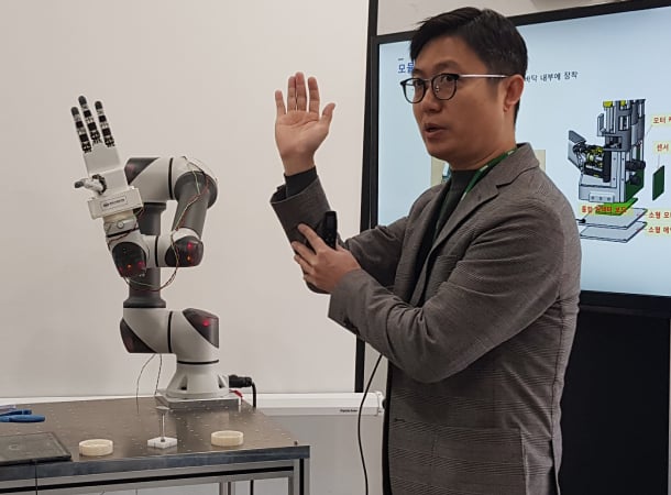 A researcher at KIMM demonstrates how the robot hand moves like a human hand, grabbing objects like eggs and scissors. Source: YONHAP