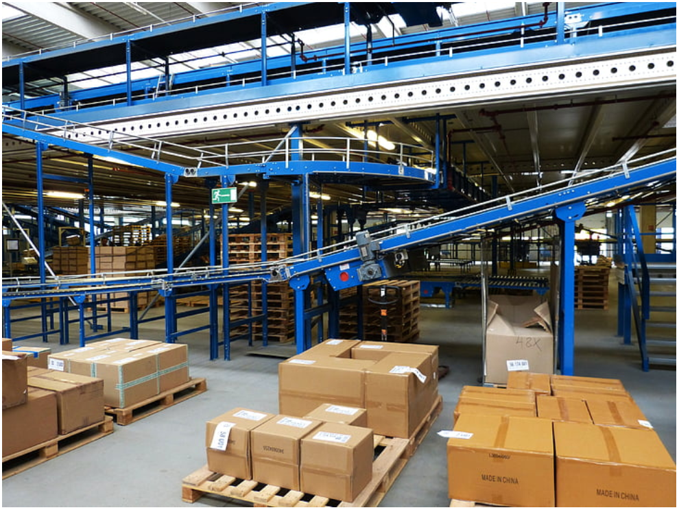 A warehouse conveyor system handling palletized boxes. Source: PickPic