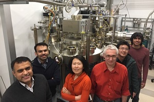 Cornell University researchers flank one of the molecular beam epitaxy systems used in their latest work. Source: Cornell University