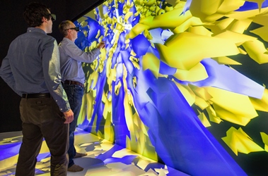 Two researchers from the U.S. National Renewable Energy Laboratory examine velocity (blue) and turbulence (yellow) in a visual simulation of a Danish wind farm. Image source: NREL, Dennis Schroeder.