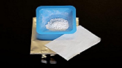 Adding powdered silica (in blue container) to the polymer layer (white sheet) that separates electrodes inside a test battery (gold bag) will prevent lithium-ion battery fires. Source: Gabriel Veith/ORNL