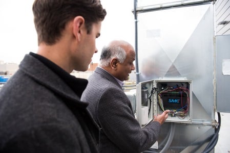  PNNL researchers Srinivas Katipamula (right) and Nick Fernandez (left) examining a control box for a commercial building&rsquo;s heating and cooling system