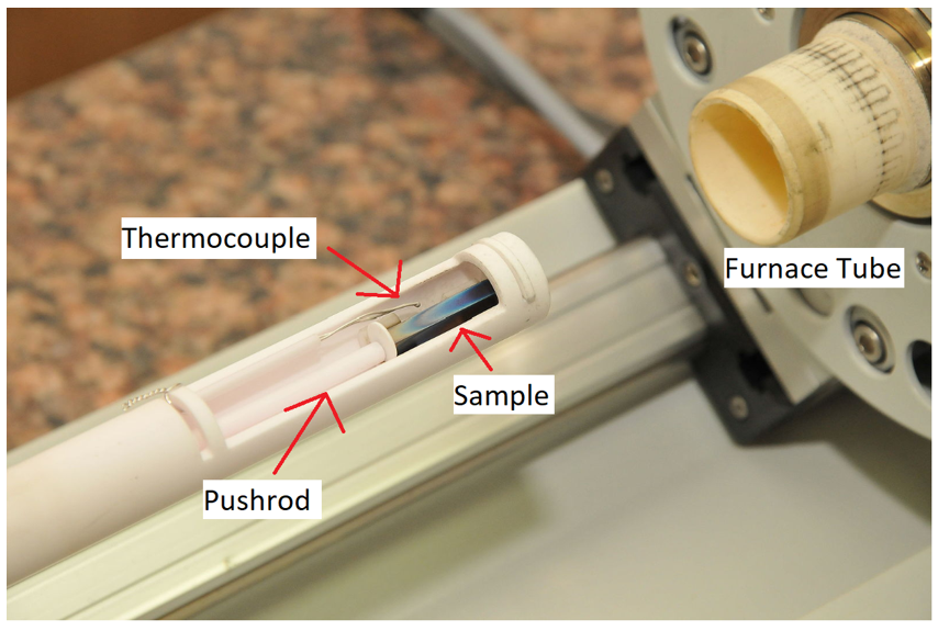 Figure 3: In this image, the furnace is shown to the right and the furnace tube on the left. Inside the furnace tube is a small steel sample, being held in place by a pushrod and the end of the tube cylinder. The furnace slides over the tube, placing the sample and control thermocouple in the heating zone of the furnace. Source: MadCAD/CC BY-SA 4.0