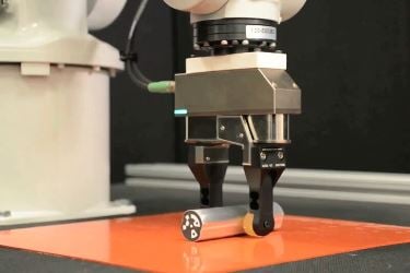 A robot grips a rod while pushing it against a tabletop, allowing the rod to rotate in the robot’s "fingers." Image credit: MIT.