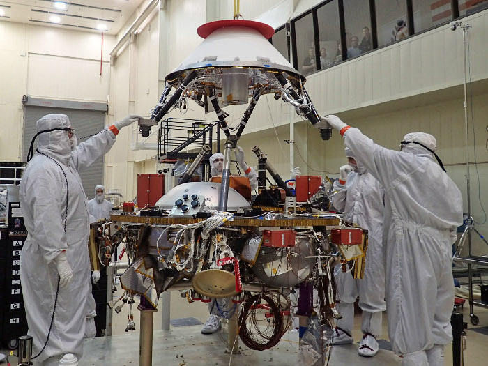 Engineers at Lockheed Martin Space Systems in Denver, CO guide the parachute cone for NASA&rsquo;s InSight spacecraft during its installation. Source: NASA/JPL-Caltech/Lockheed Martin