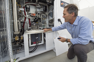 Jack Brouwer, associate director of UCI's Advanced Power and Energy Program, examines an electrolyzer, which uses excess electricity to split water into oxygen and hydrogen. Image credit: Steve Zylius/UCI.