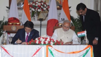 Japanese Prime Minister Shinzo Abe and Indian Prime Minister Narendra Modi sign the agreement as an aide watches. Image source: Indian Prime Minister’s Office.