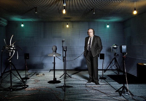 Klaus Genuit photographed in an anechoic chamber with several loudspeakers to simulate a virtual acoustical scenery, as well as an artificial head for binaural recording. Credit: Genuit