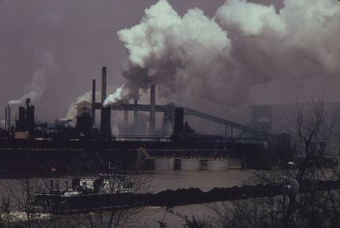 In this 1973 image, a coal barge on the Monongahela River in Pennsylvania passes a US Steel coke plant. Credit: Wikipedia