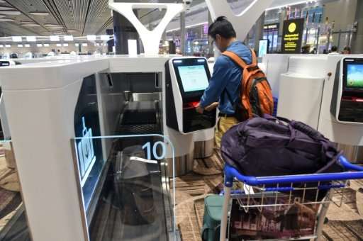 A passenger checks in his luggage using an automated booth at the newly opened Changi International Airport's Terminal 4 in Singapore. Source: AFP