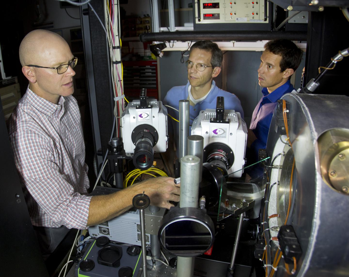 Sandia National Laboratories researchers Scott Skeen, left, and Lyle Pickett, center, and former Sandia researcher Julien Manin discuss a new optical device developed at Sandia that can quantify the formation of soot. (Dino Vournas)
